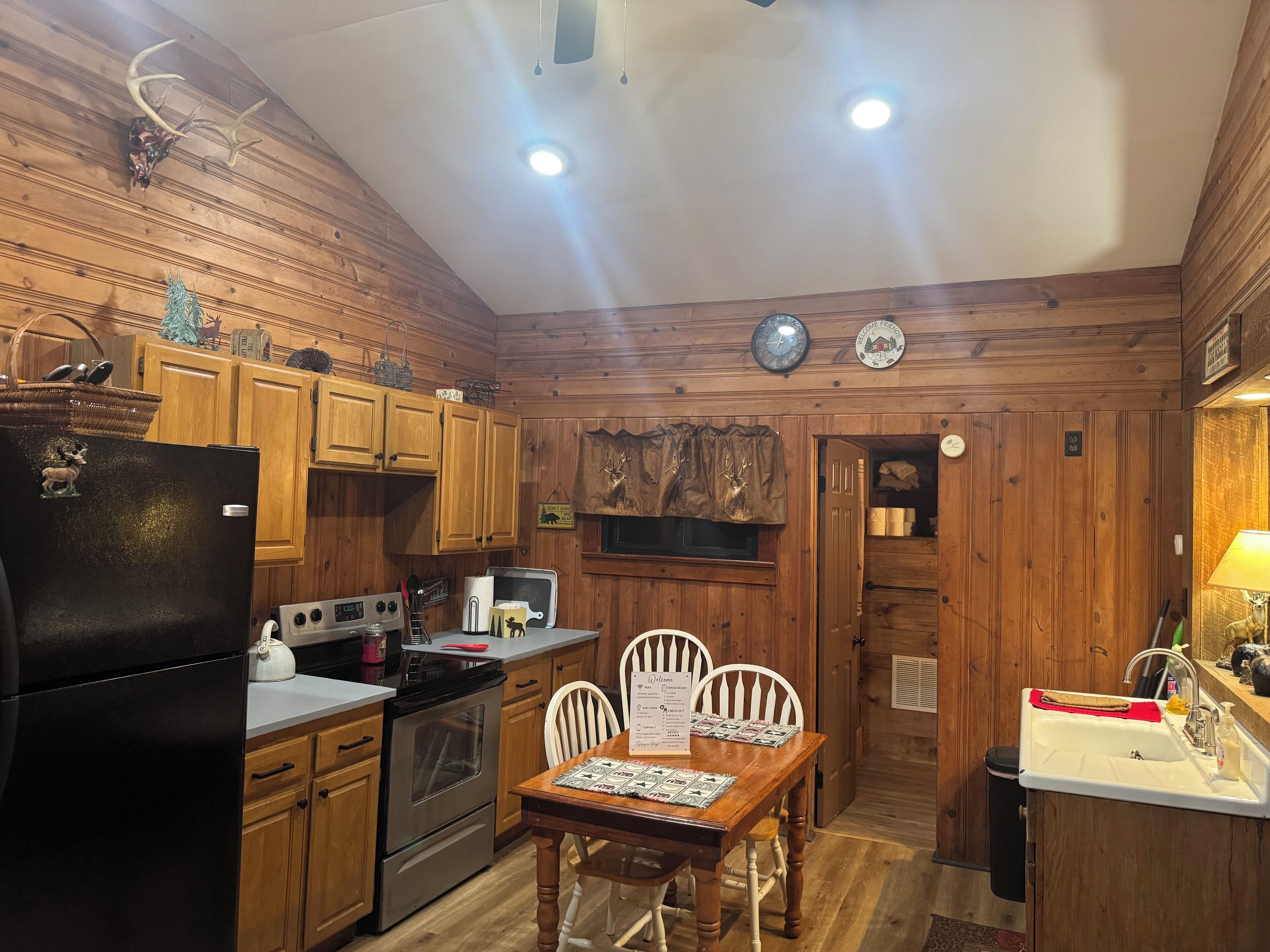A wooden cabin kitchen with a refrigerator, stove, and dining table with chairs.