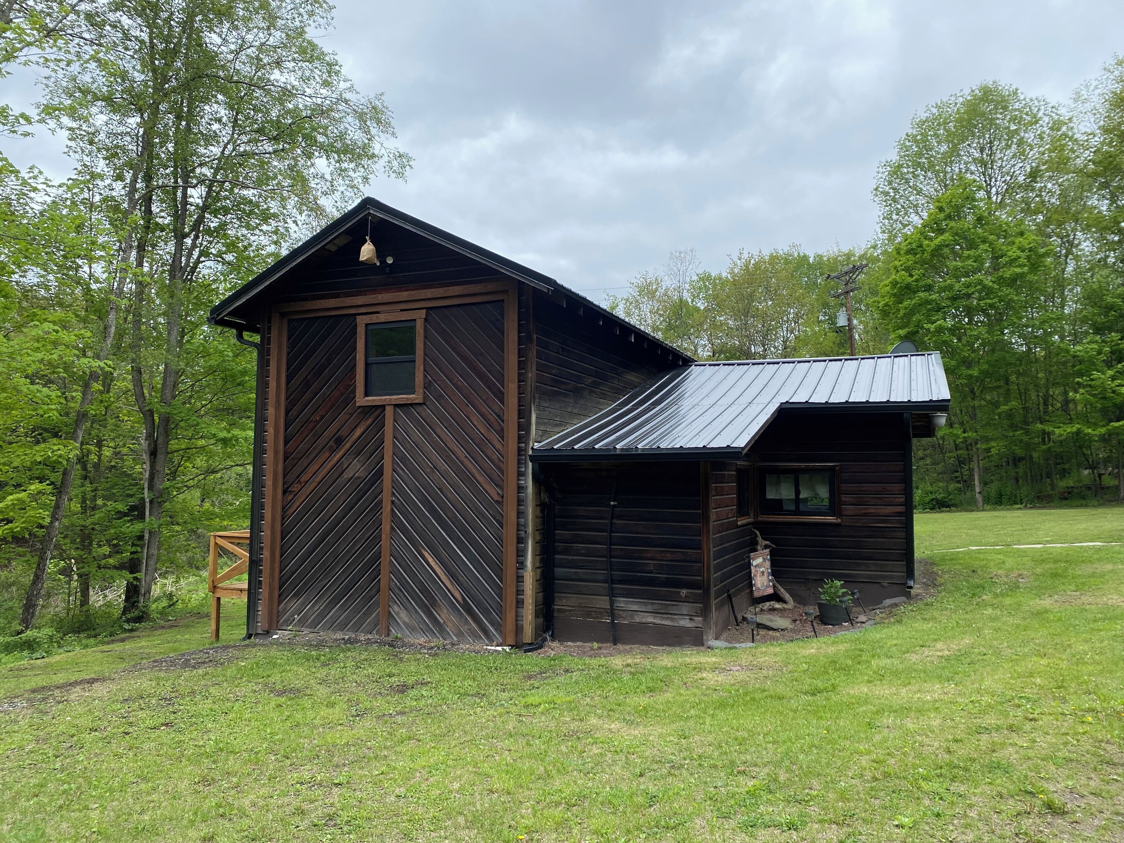 Une grange rustique en bois, dotée d’une grande porte et d’une petite dépendance attenante.