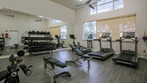 A gym with treadmills, weight machines, and dumbbells.