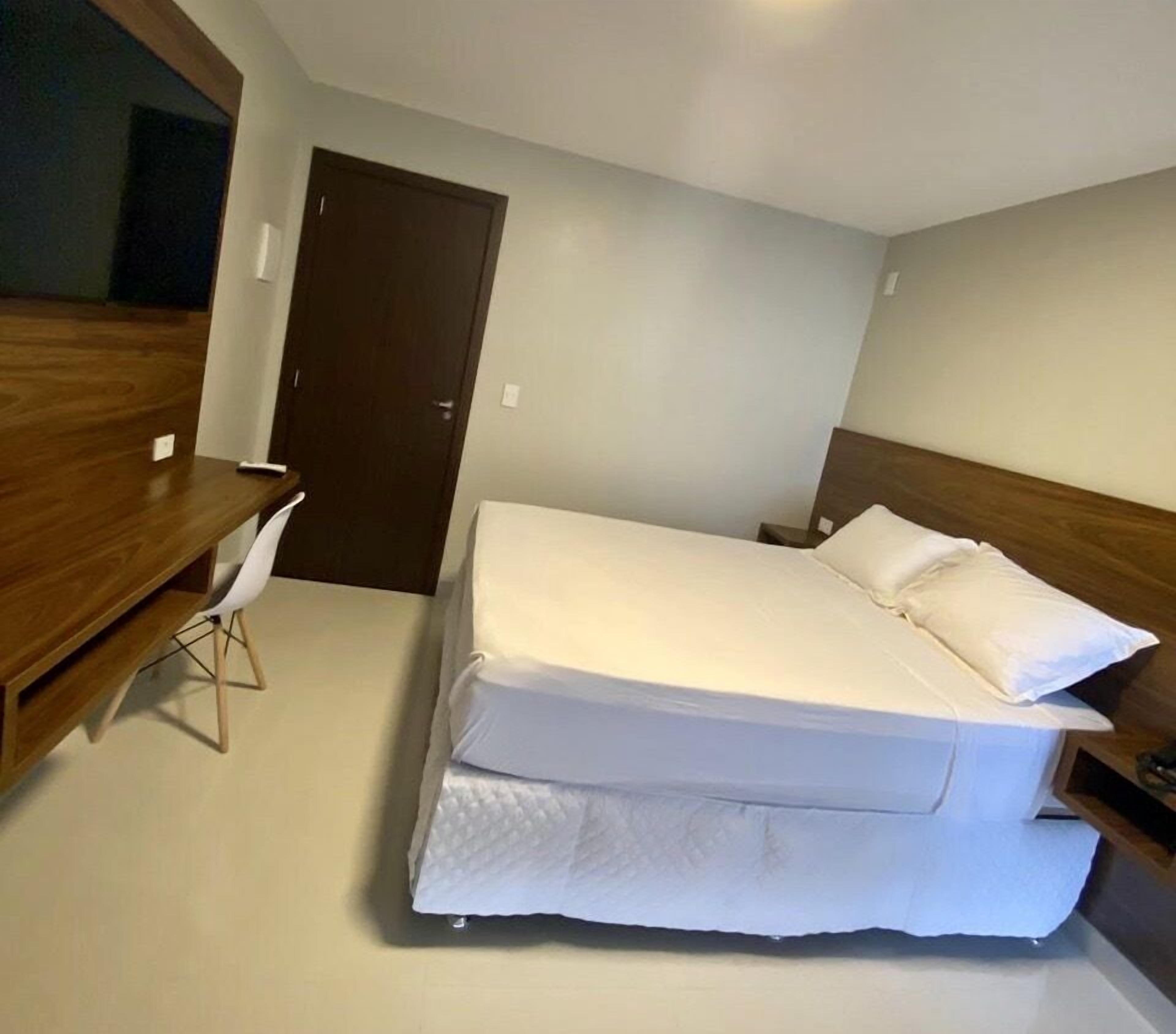 Un dormitorio con cama, escritorio y silla.