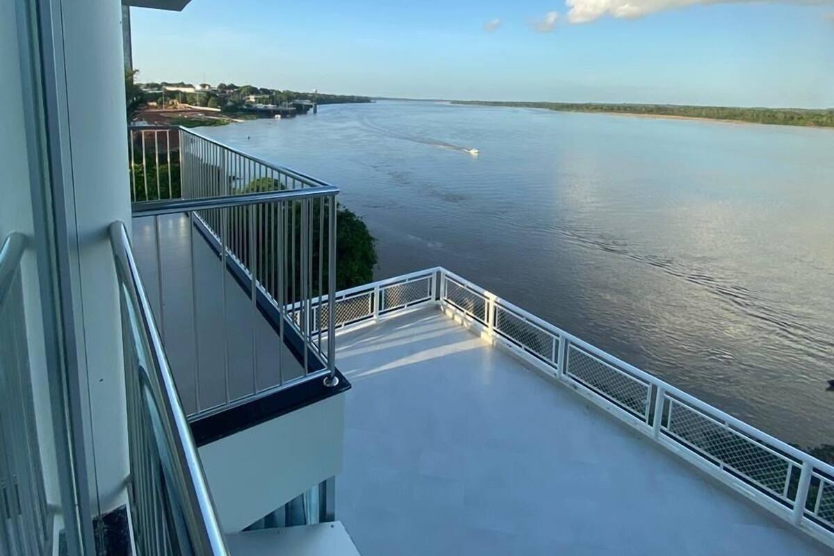A balcony with a view of a calm river and distant shoreline.