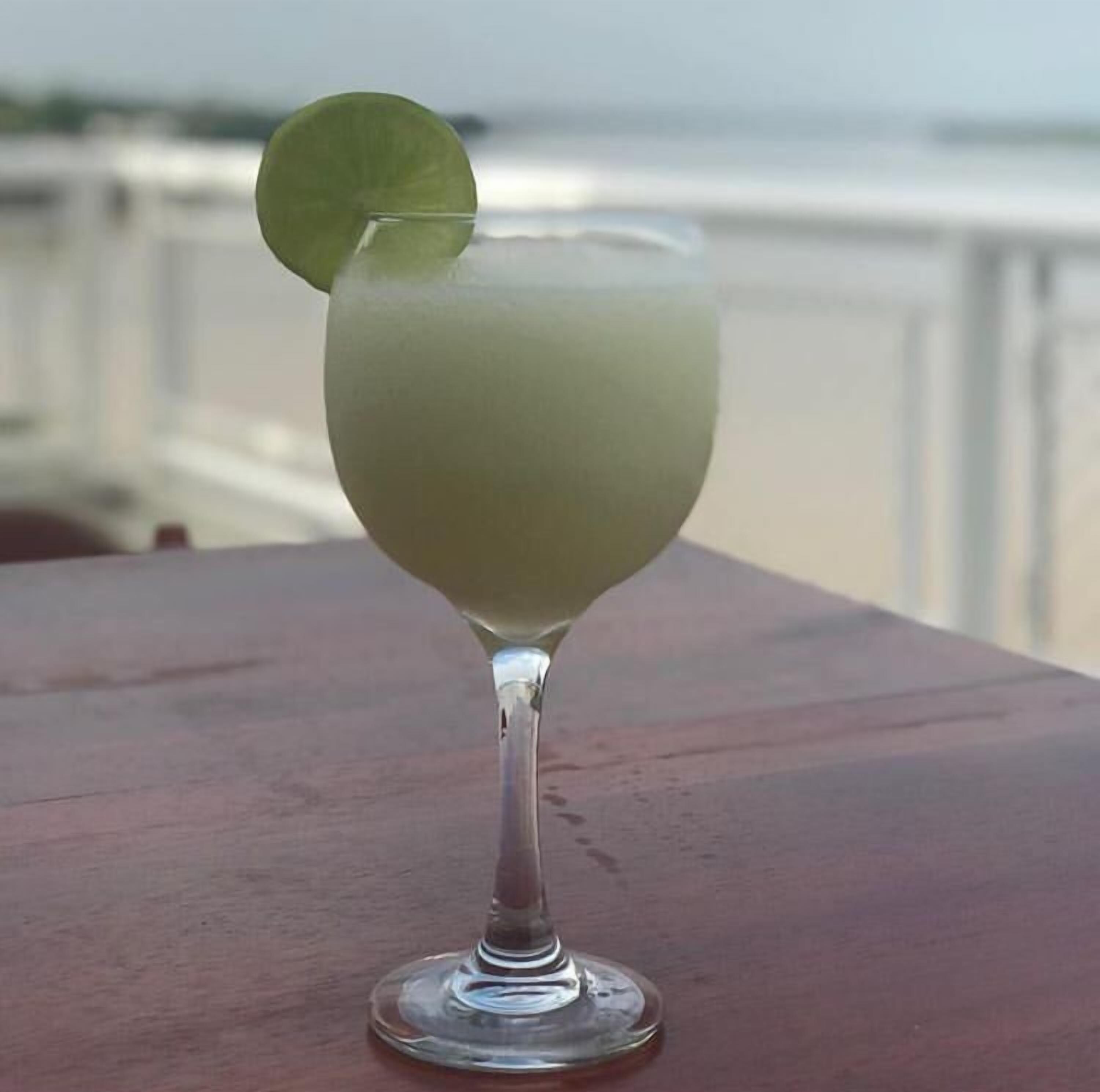 A clear glass with a lime garnish on a wooden table.