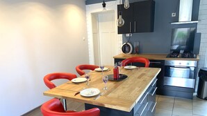 A modern kitchen with a dining area, featuring a wooden table, red chairs, and stainless steel appliances. - Heart of Metz, 2 rooms free parking wifi 75m² "Le Saint Bernard (Metz)