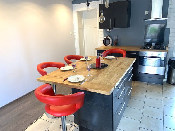 A modern kitchen with a dining area, featuring a wooden table, red chairs, and stainless steel appliances. - Heart of Metz, 2 bedrooms, free parking, Wi-Fi, 75 m² "Le Saint Bernard" (Metz)