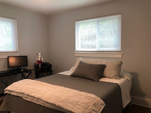 A bedroom with a bed, a desk with a computer, and two windows with blinds. - HICKORY HOUSE 4 SHORT AND LONG TERM RENTAL (Hickory)