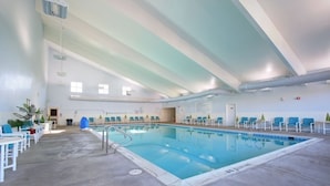 An indoor swimming pool with a clear water surface, surrounded by lounge chairs and tables. - Sea Scape - Multiple Pools, Amenities, and Close to Beach! (Kitty Hawk)