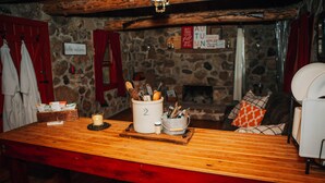 A wooden bar table with a candle, a salt and pepper shaker, and a container of utensils. - The Stone Cabin; Off-the-grid experience with outhouse (Houston)