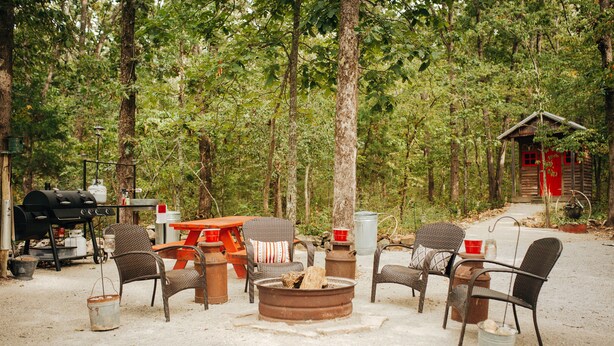 A campsite with a fire pit, chairs, a table, and a grill. - The Stone Cabin; Off-the-grid experience with outhouse (Houston)
