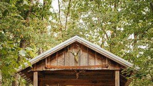 A rustic cabin with a red door and windows, surrounded by trees. - The Stone Cabin; Off-the-grid experience with outhouse (Houston)