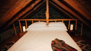 A bed in a room with a sloped ceiling and stone walls. - The Stone Cabin; Off-the-grid experience with outhouse (Houston)