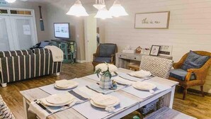 Un coin repas avec une table en bois dressée pour six personnes, entourée de chaises en osier.