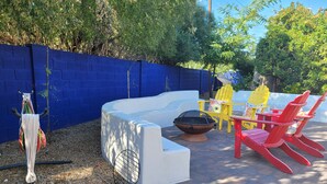 A patio with a white outdoor seating area, a fire pit, and colorful Adirondack chairs. - Garden-front studio  (Phoenix)