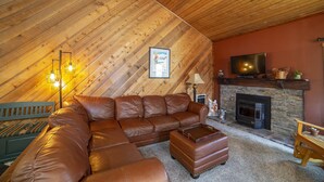 A cozy loft-style living room with a wooden ceiling, a sectional sofa, a fireplace, and a television. - Bright Cozy Snowcreek 1Bed/1Bath WIFI (Mammoth Lakes)