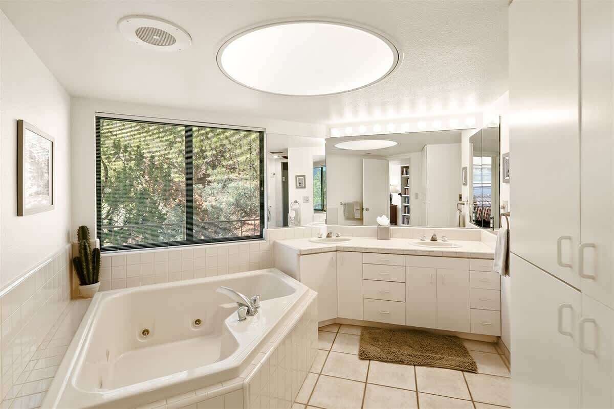Un baño moderno con una bañera independiente, un amplio ventanal con vistas y un tocador con espejo.