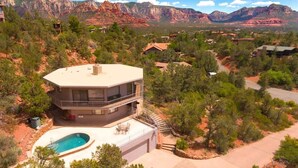 Une maison à deux étages avec une piscine, entourée d’arbres et de montagnes.