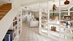 Un vaste espace de vie comprenant un escalier, des étagères ouvertes et une vue dégagée grâce à de grandes fenêtres.