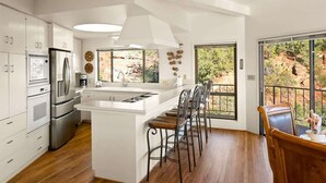 Une cuisine moderne avec des meubles blancs, des appareils en acier inoxydable et un îlot central doté de tabourets de bar.