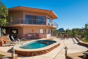 Una casa de dos pisos con piscina, zona de estar exterior y balcón.