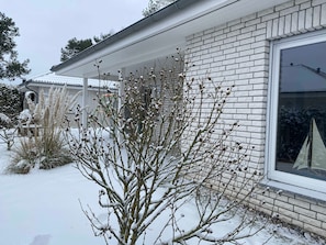 Ein Haus mit Backsteinfassade, einem Fenster mit Segelmotiv und verschneitem Untergrund.