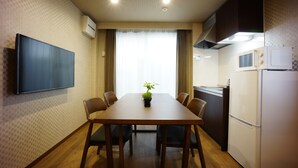 A compact kitchen with a dining table, chairs, a flat-screen TV, and a microwave. - Rona Hotel (Tokyo)