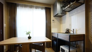 A compact kitchen with a wooden table, a microwave, and a sink. - Rona Hotel (Tokyo)