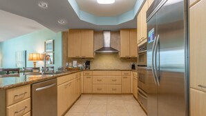 Une cuisine moderne avec des meubles en bois, un réfrigérateur en acier inoxydable et un four encastré.