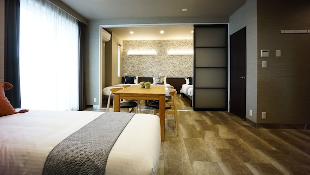 A modern hotel room with a large bed, a wooden dining table, and a separate seating area. - The South Hotel Tokyo (Tokyo)