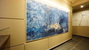 A corridor with a large abstract painting on the wall, a map on the right, and a staircase on the left. - The South Hotel Tokyo (Tokyo)