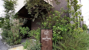 A sign for The South Hotel in Tokyo, surrounded by greenery and a stone pathway. - The South Hotel Tokyo (Tokyo)