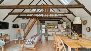 A spacious loft with exposed wooden beams, a wooden dining table, and a cozy seating area with a sofa and chairs. - Stunning home in Glesborg with WiFi (Glesborg)