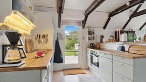 A kitchen with wooden cabinets, a coffee maker, and a view of the outdoors. - Stunning home in Glesborg with WiFi (Glesborg)