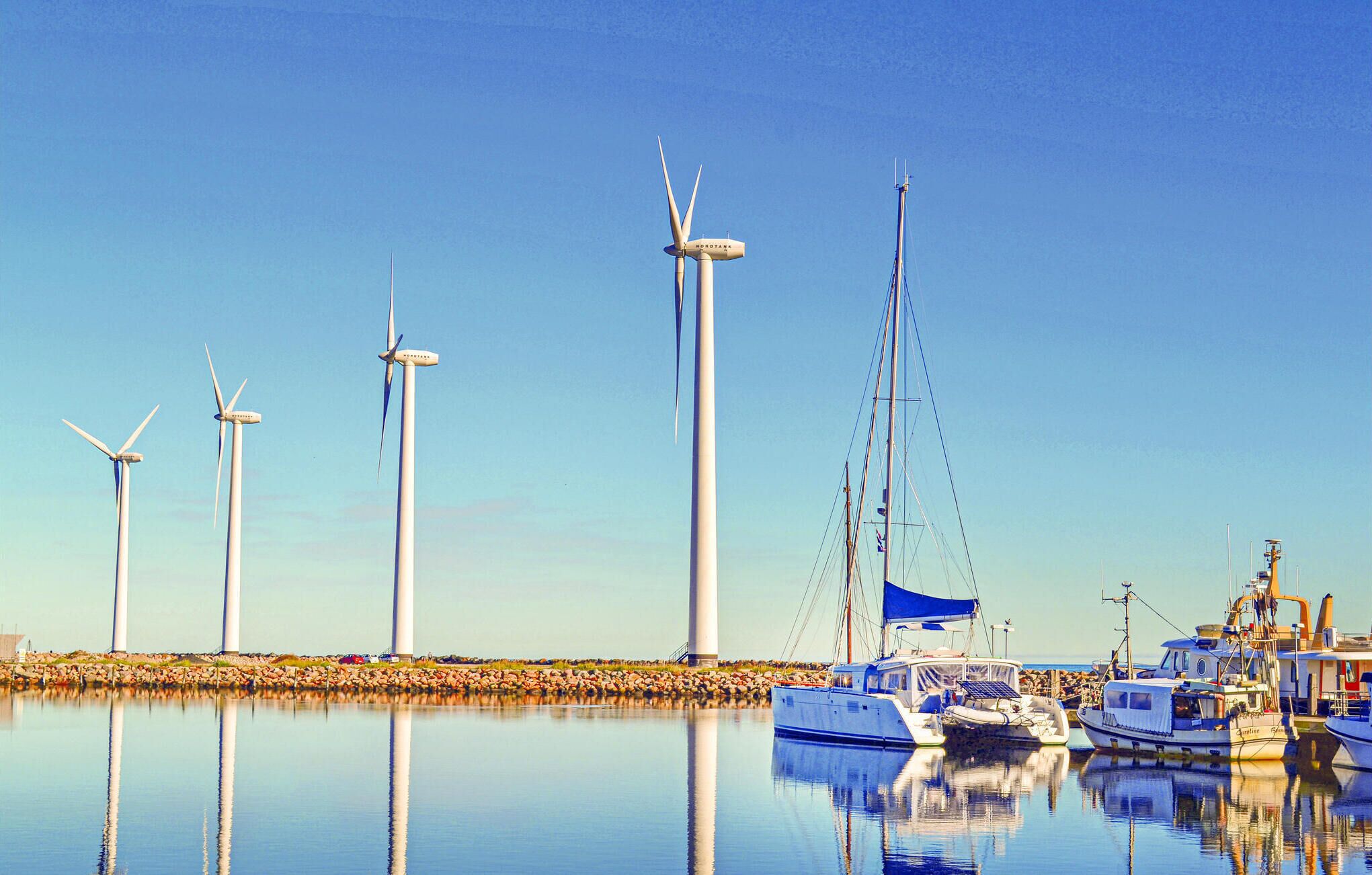 A marina with several wind turbines and boats.