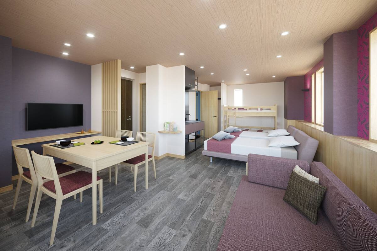 A modern, well-lit room with a dining area, bunk beds, and a sofa.