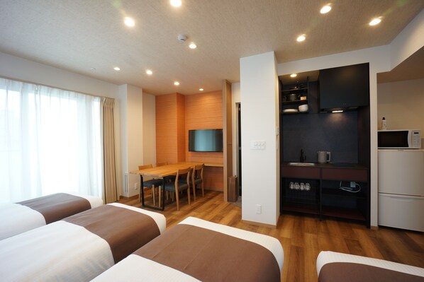 A hotel room with a bed, a desk, and a kitchenette.