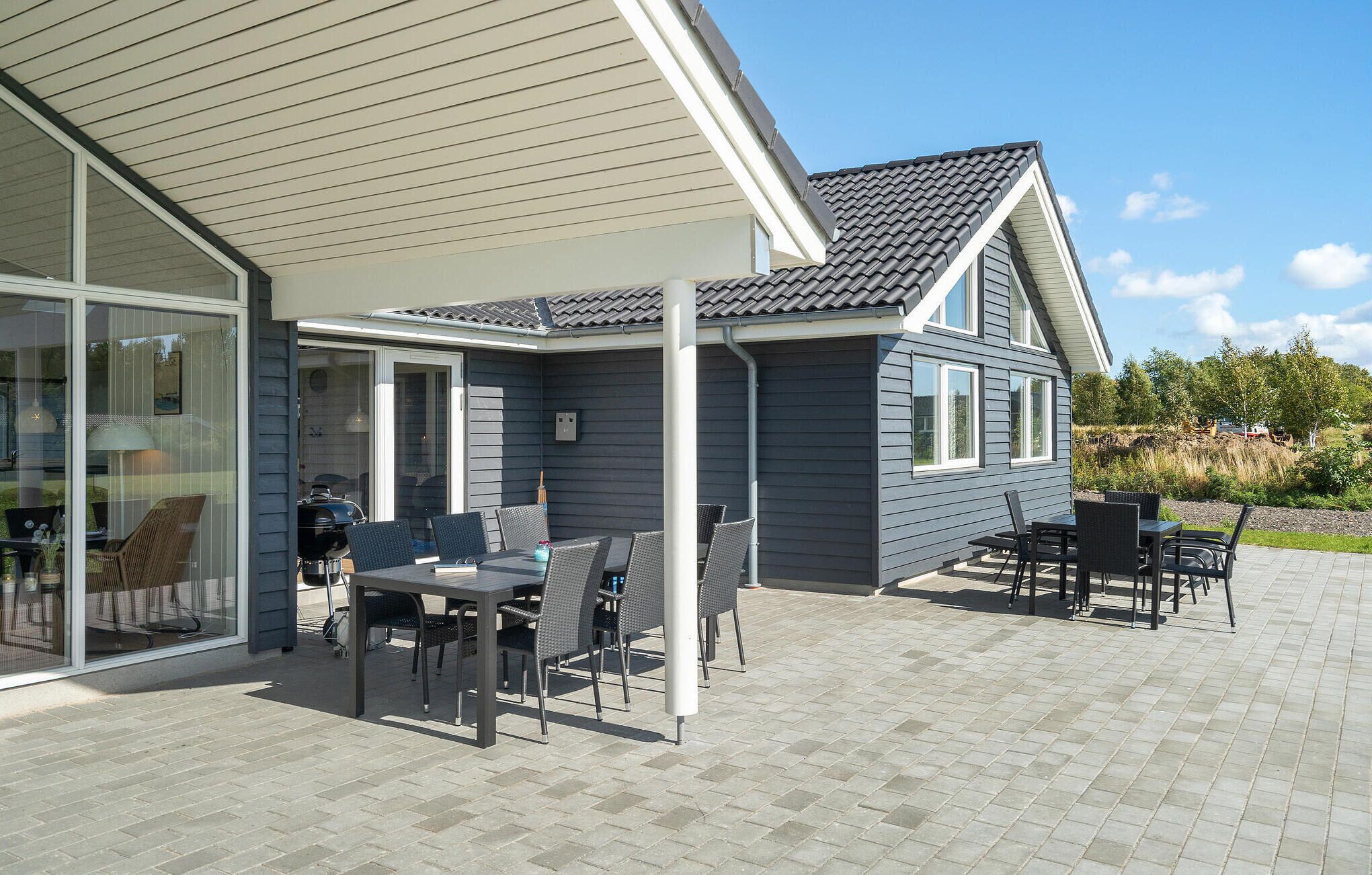 A modern house with a patio area featuring outdoor furniture and a glass door leading to a covered porch.