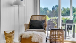 Une chaise en osier avec un plaid en fourrure, un panier en osier et une table ronde en osier agrémentée de bougies et de fleurs.