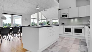 Une cuisine moderne avec des meubles blancs, un grand îlot central et des fours encastrés.