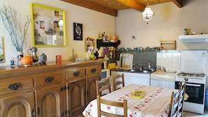 Una cocina con armarios de madera, una mesa de comedor con mantel floreado y una estufa.
