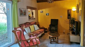 Un salón acogedor con techo de madera, un sofá con cojines estampados, una mesita y una chimenea.