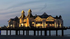 A waterfront building with a pier, featuring multiple towers and large windows.