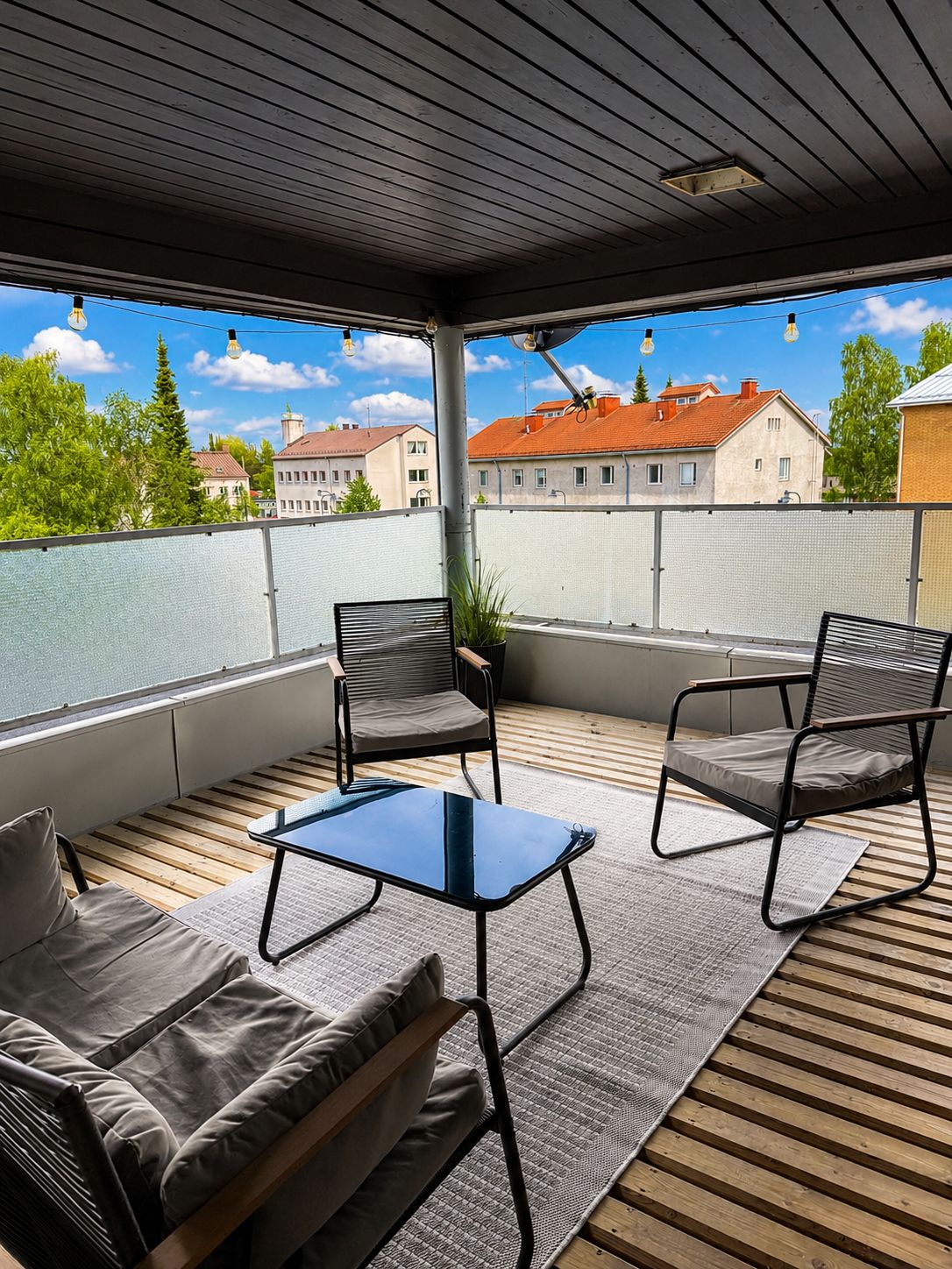 A covered outdoor seating area with a sofa, two chairs, and a small table.