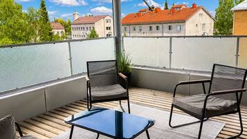 A covered outdoor seating area with a sofa, two chairs, and a small table.