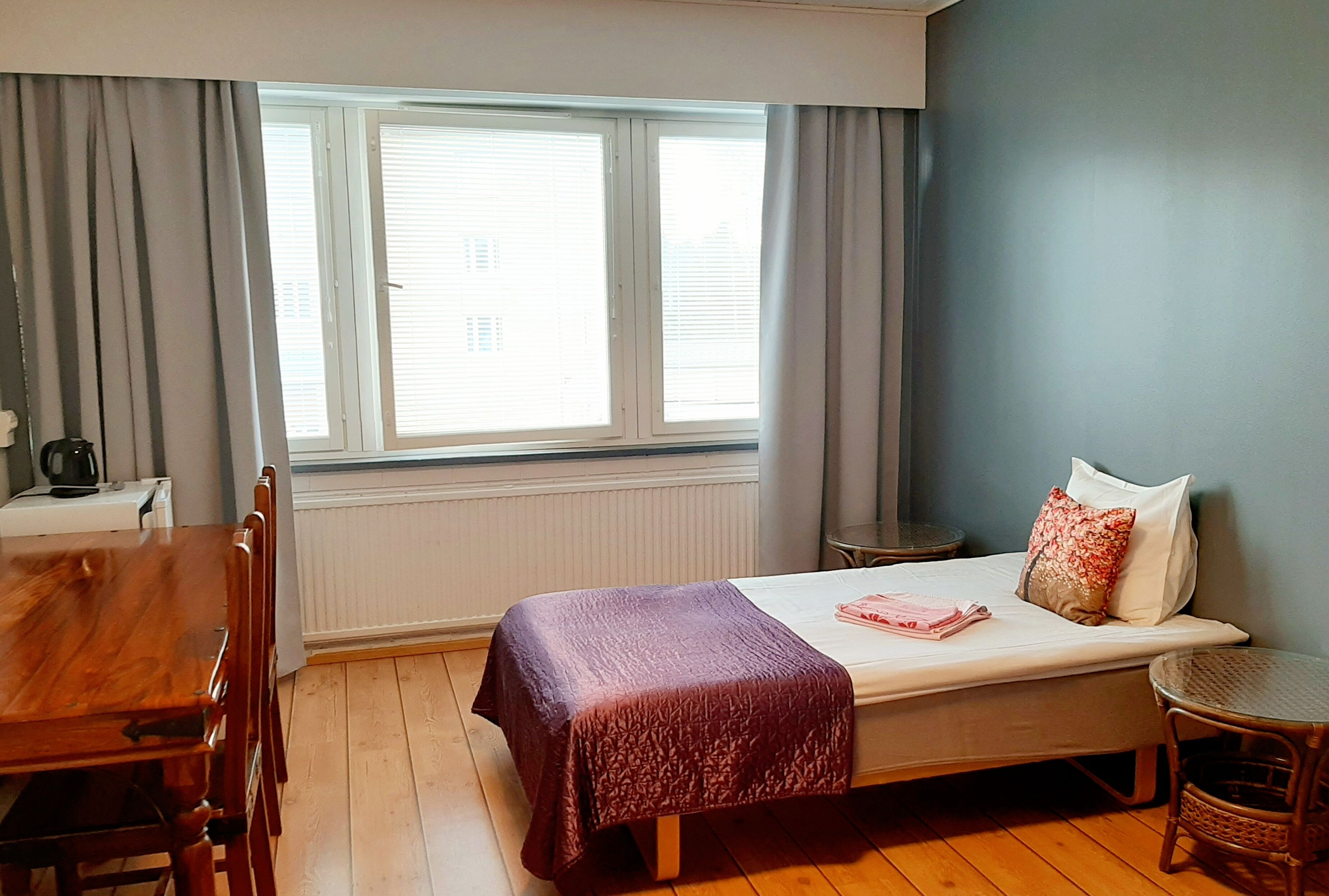 A room with a bed, a wooden table, and a chair.