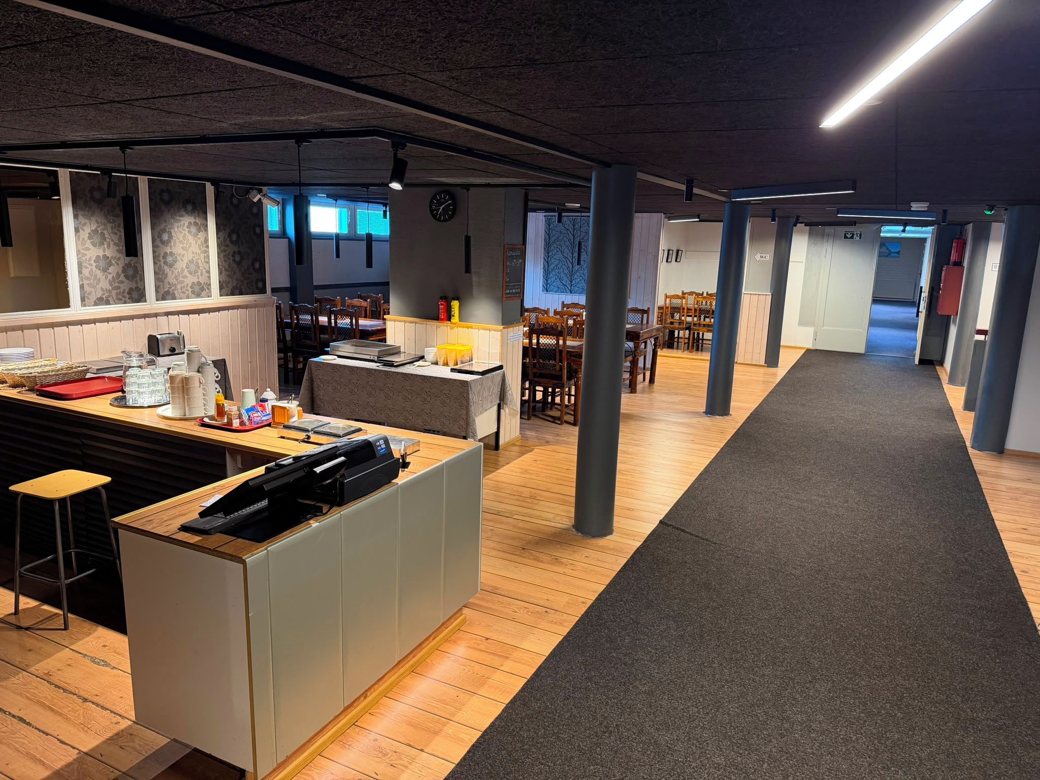 Een modern interieur met een receptiebalie, houten vloeren en een bekleed pad dat naar een zithoek leidt.