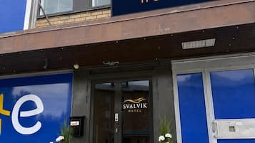 Svalvik-hotellin ulkoasu: selkeä kyltti, lasinen sisäänkäynti ja kaksi ruukussa olevaa kasvia sisäänkäynnin edessä.