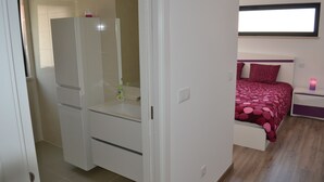 Un dormitorio con cama, mesita de noche, espejo y armario.