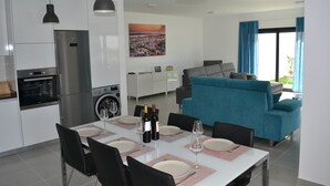 Una cocina moderna con un refrigerador de acero inoxidable, una lavadora y un comedor con una mesa dispuesta para seis personas.