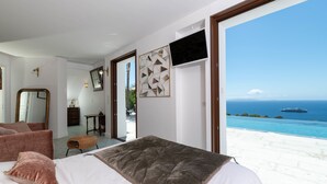 Un dormitorio con cama, un banco y vistas al océano.