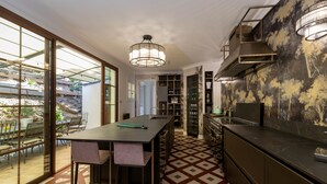 Una cocina moderna con una isla grande, estantes empotrados y un comedor con pared de vidrio que da a un jardín.