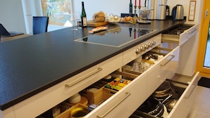 Une cuisine moderne avec un plan de travail noir, des meubles blancs et des appareils électroménagers intégrés.